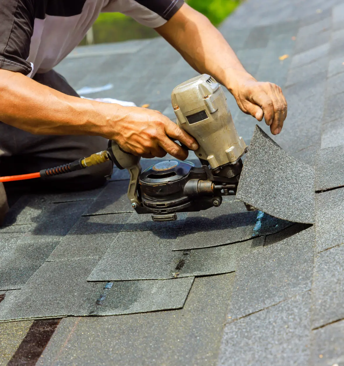 Group 8 (8) (8) Worker using nail gun on roof shingles.